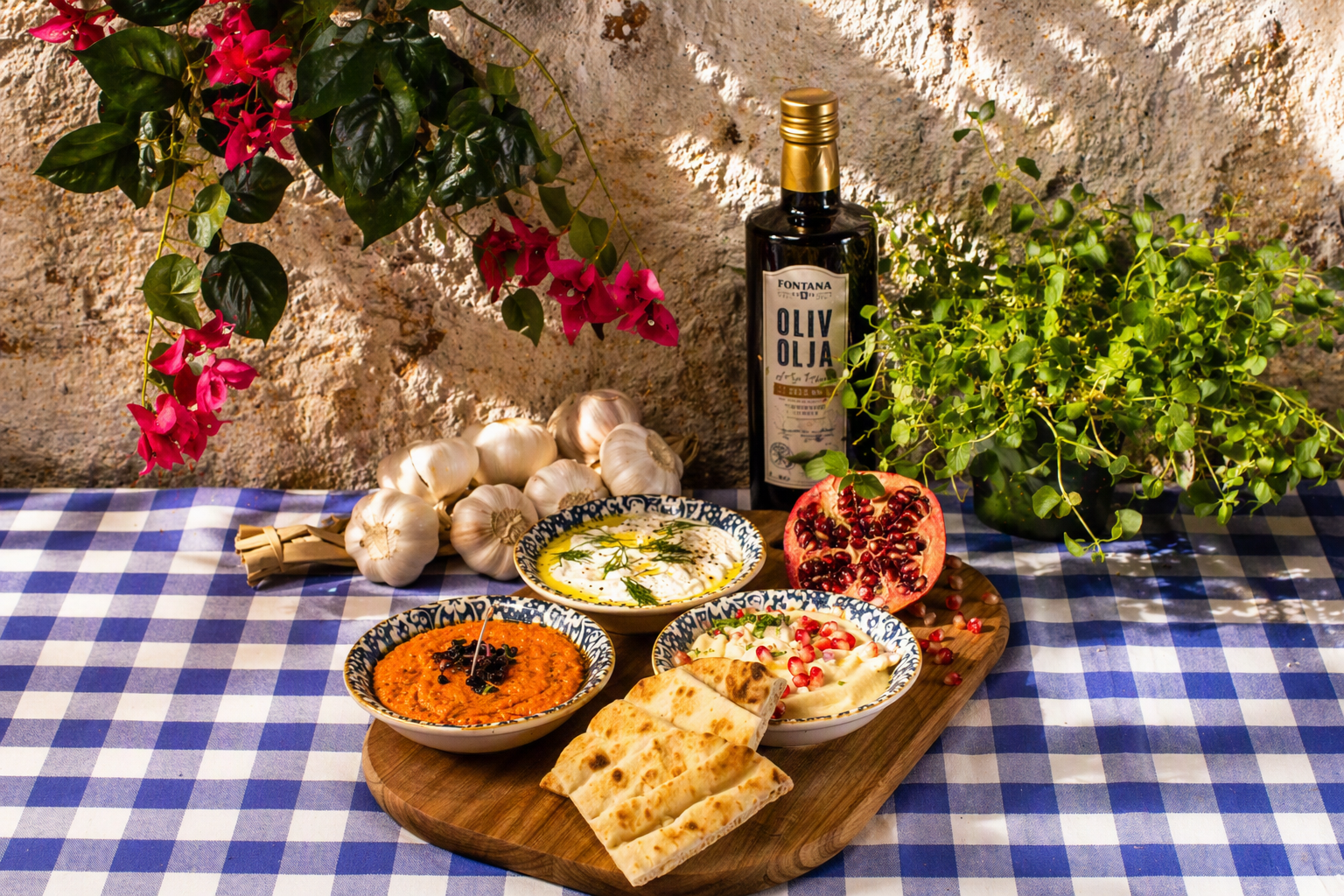 Mezes bestående av Hummus, Tzatziki, fetaoströra med paprika. Serveras på en bricka i en grekisk miljö.